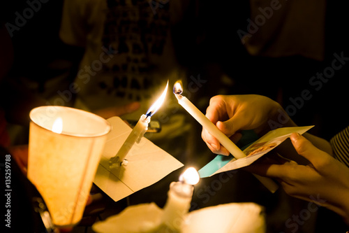 фотографія People holding candle vigil in darkness seeking hope, worship, prayer