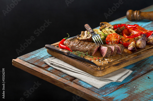 Sliced steak grill with grilled vegetables on the wooden table
