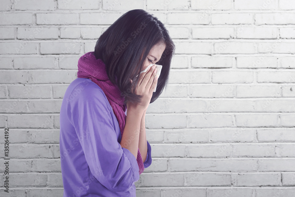 Sick asian woman with flu and fever holding tissue in nose