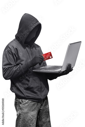 Hacker man wearing anonymous mask holding laptop and credit card while standing