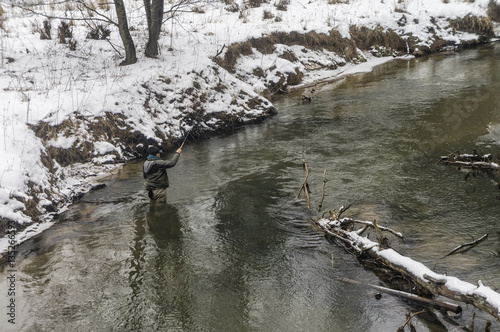 Fisherman with rod on a winter river. Tenkara fishing. photo