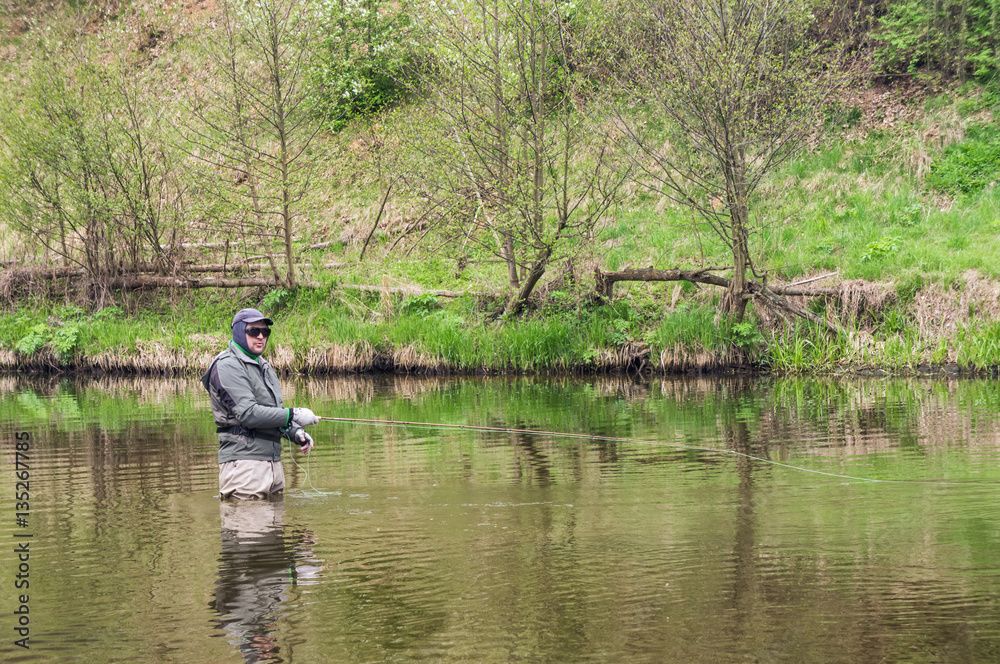 Fisherman fishing on a small spring river. Fly fishing.