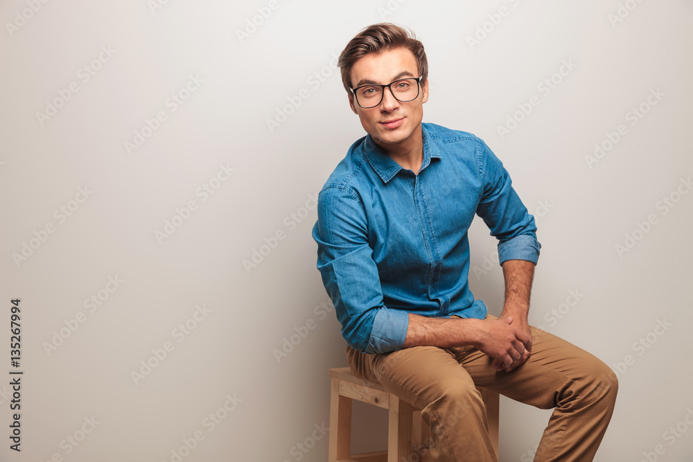 young casual man with glasses resting on a chair young casual man with glasses resting on a chair