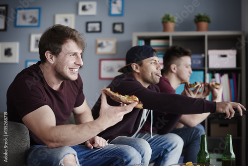 Guys enjoying junk food and watching tv
