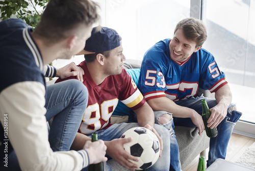 Friends seated on a sofa and watching soccer game