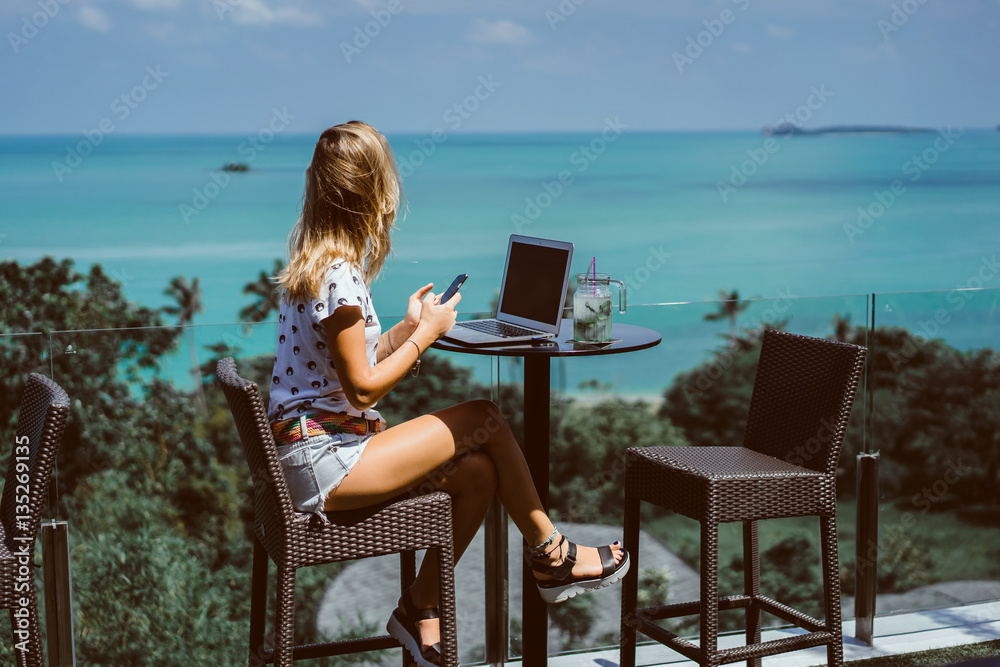 Fototapeta premium young pretty brunette woman eat chocolate in cafe, using smartphone and laptop touch screen display, sweet food, tasty breakfast, close up portrait, hipster girl, fanny, drink coffee 