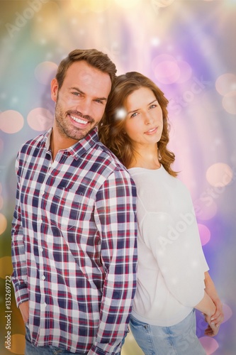 Composite image of happy young couple standing back to back