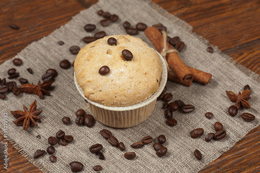 Tasty muffin cakes on burlap, spices and coffee beans