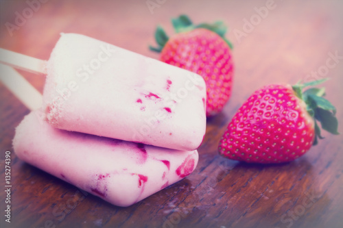 Homemade strawberry ice lolly on rustic background
