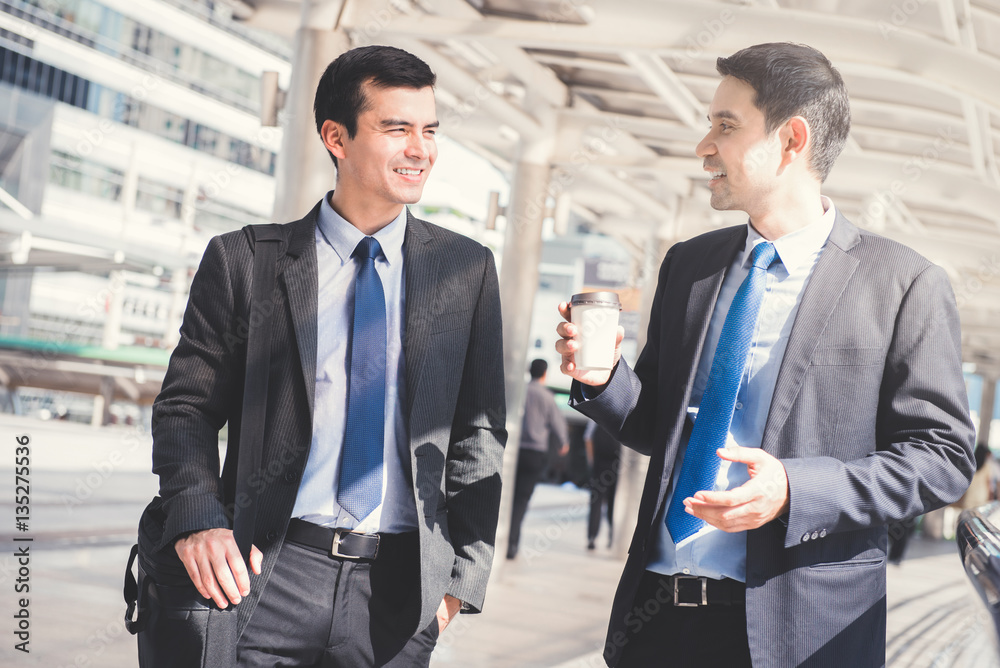 Interracial businessmen as colleague, walking and talking in the morning Interracial businessmen as colleague, walking and talking in the morning