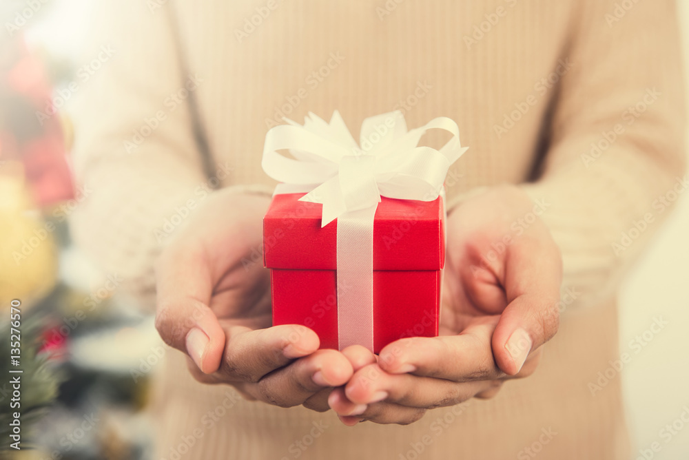Woman hands giving red gift box Woman hands giving red gift box
