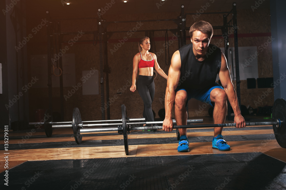 Fototapeta premium Group of sporty adults exercising with barbells