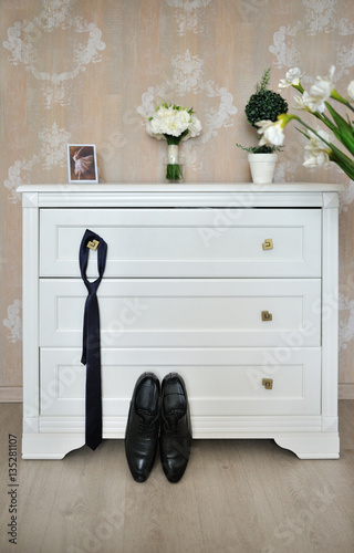 Shoes, tie and wedding bouquet in the room of groom