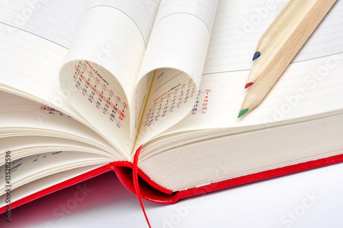 Date in red notebook, heart of pages and color pencils.