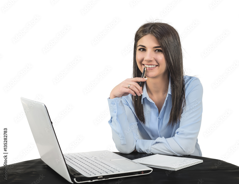 A cheerful young girl sitting in the office with a laptop and a pen. A white isolated background. A cheerful young girl sitting in the office with a laptop and a pen. A white isolated background.