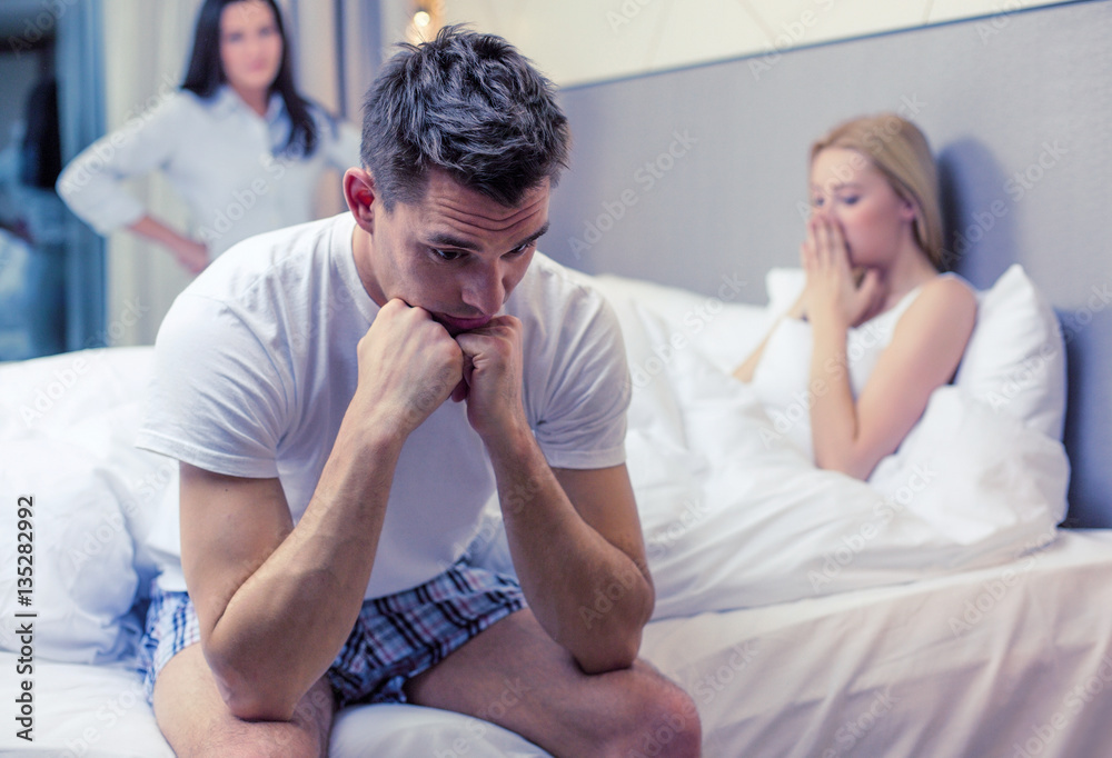 man sitting on the bed with two women on the back man sitting on the bed with two women on the back