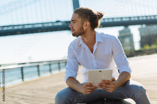 Young businessman in NYC holding a digital device