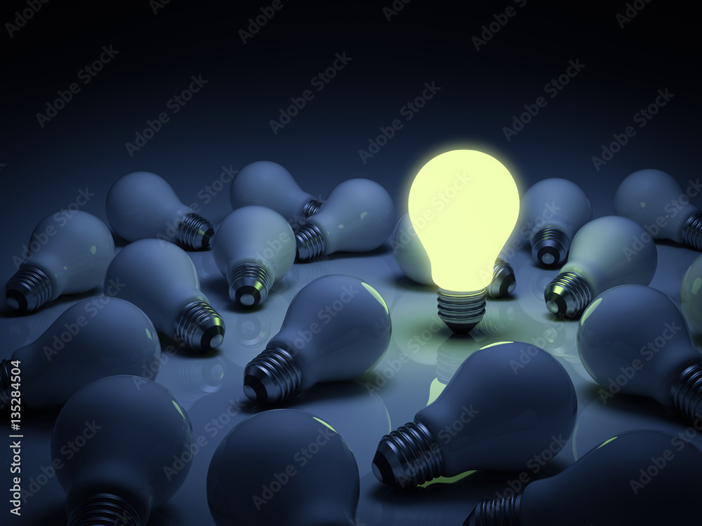 One lit glowing light bulb standing out from the unlit incandescent