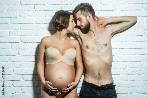 bearded slim man and pretty pregnant woman with round belly photo