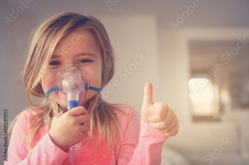 Photo Little girl using inhaler.