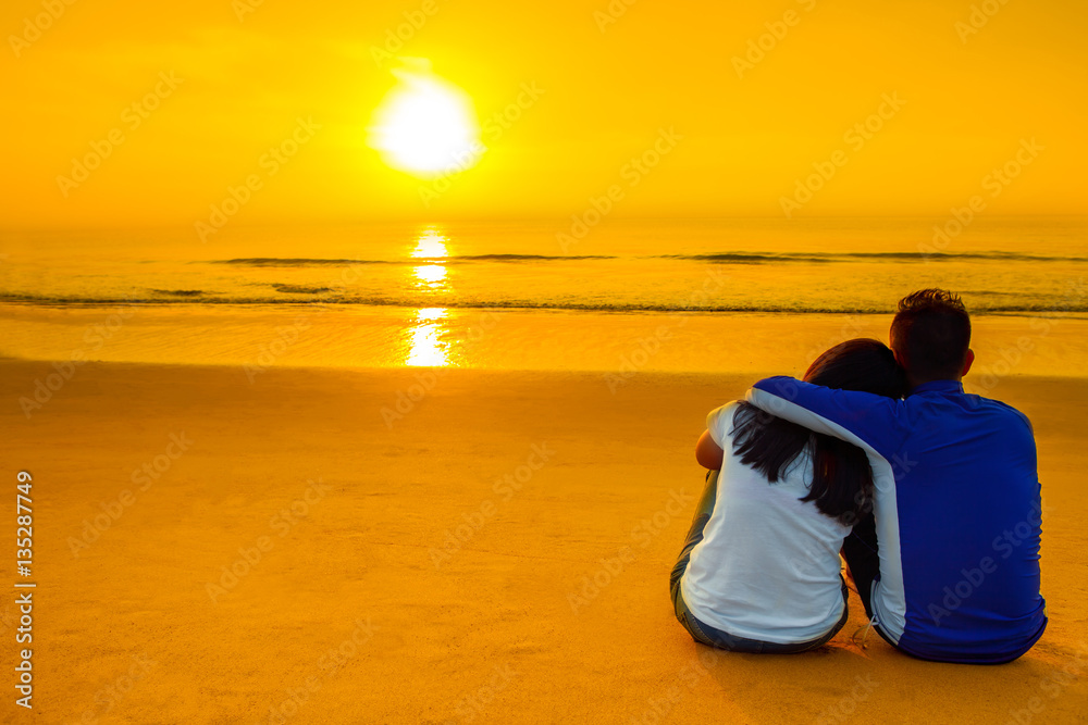 Romantic hugging Young couple watching the sunset on the beach