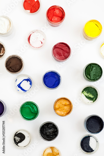 Open gouache jars on a white background, flat lay composition, top view, vertical