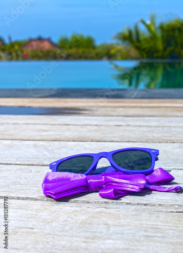 Sunglasses and bow tie near the pool
