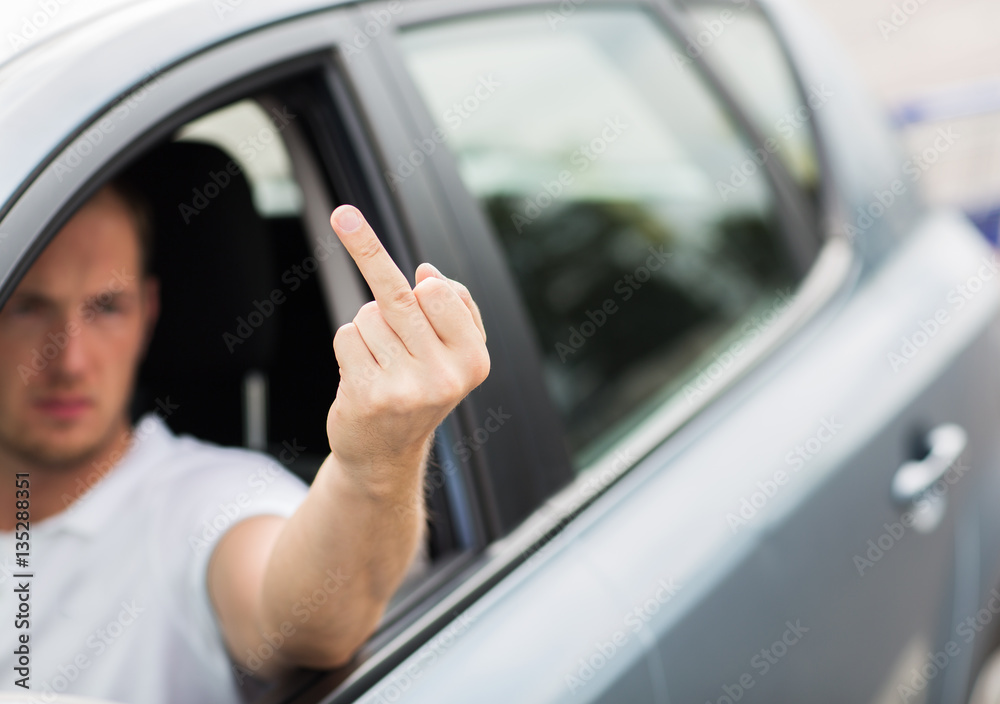 close up of man driving car showing middle finger