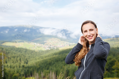 Outdoors portrait of young smiling woman in mountains with copy space