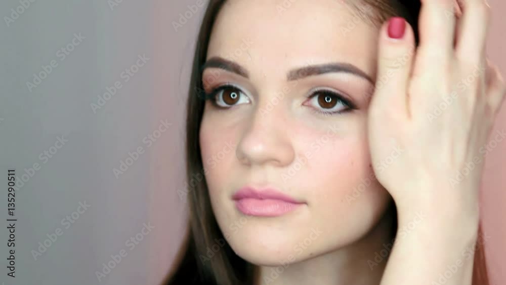 Portrait of pretty, sensual woman with beautiful make-up and elegant hairstyle looking at her reflection in mirror.