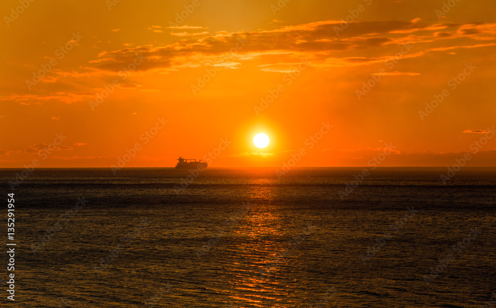 Cargo ship on the horizon at sunset