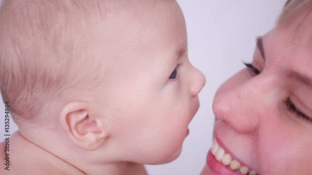 happy mother kissing her son's baby in studio on white background