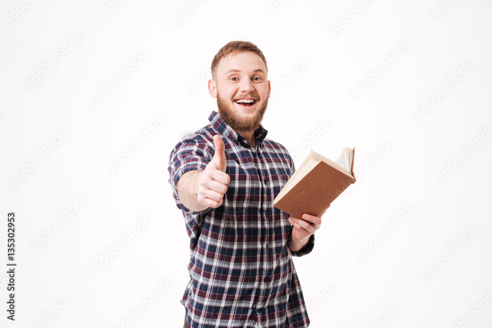 Smiling Bearded man holding book and showing thumb up Smiling Bearded man holding book and showing thumb up