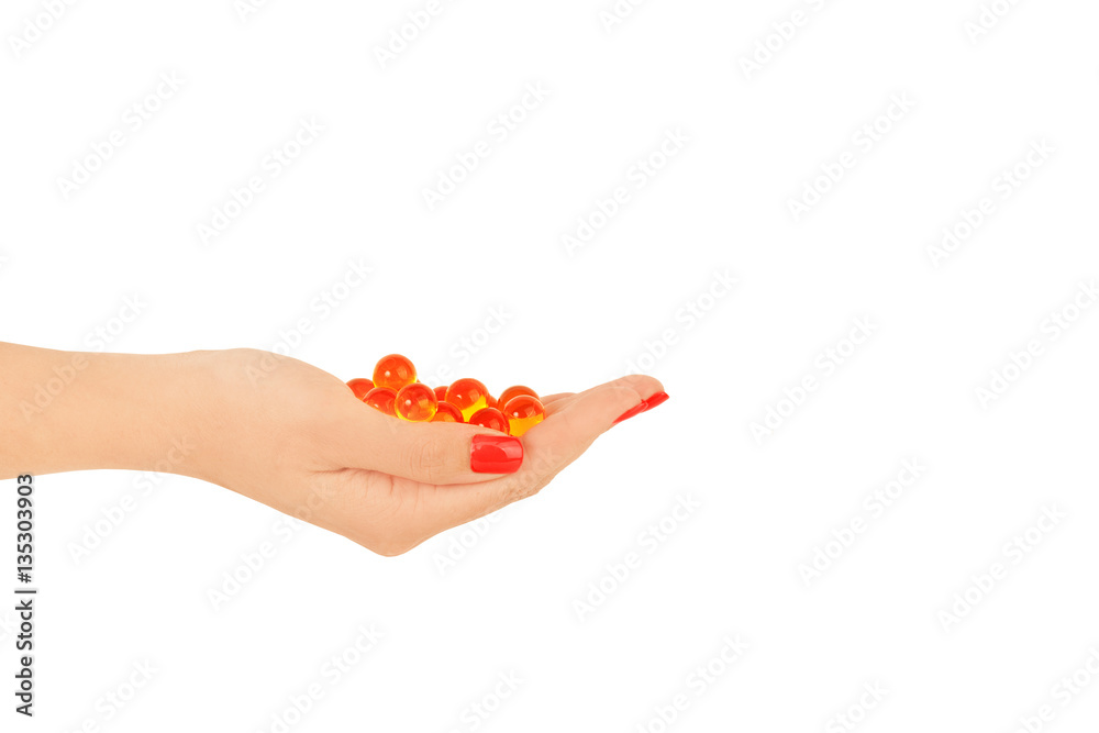 Mano de mujer sosteniendo unas cápsulas naranjas sobre fondo blanco liso y aislado. Vista de frente y de cerca. Copy space Mano de mujer sosteniendo unas cápsulas naranjas sobre fondo blanco liso y aislado. Vista de frente y de cerca. Copy space