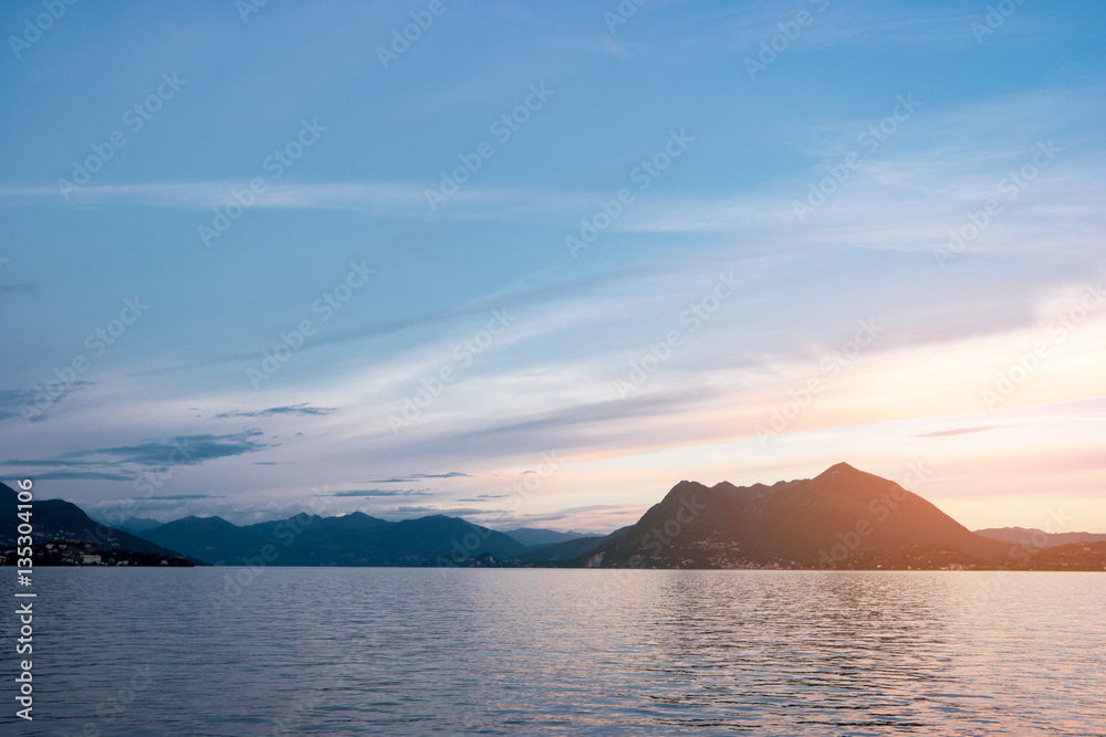 Water, hills and sky. Mountains and town at distance. Lake Maggiore in summer.