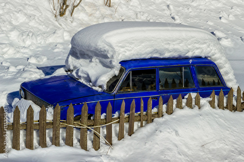 Old car covered with a thick layer of snow