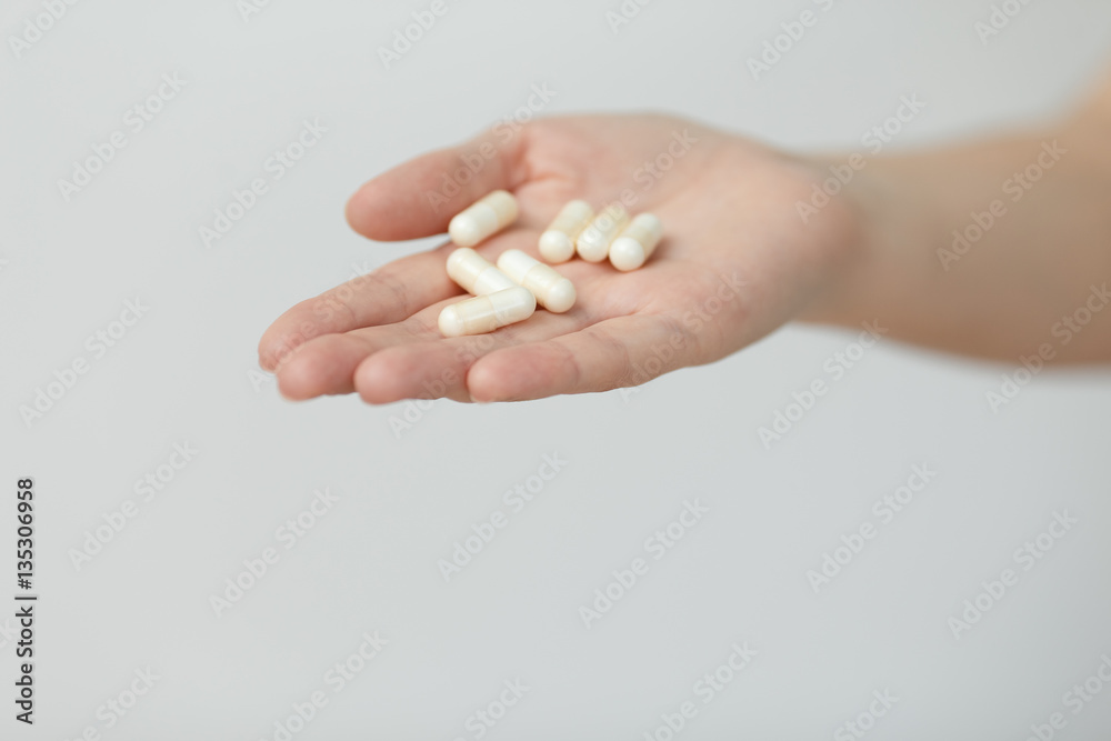 Hand is giving capsules on white background.