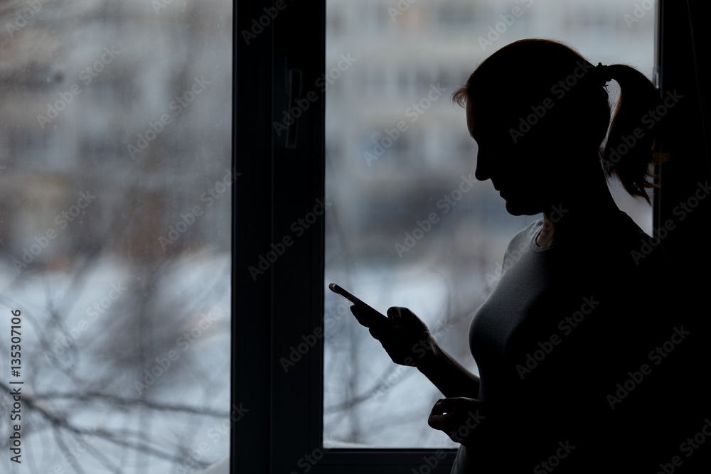 woman using smart phone at window house background.