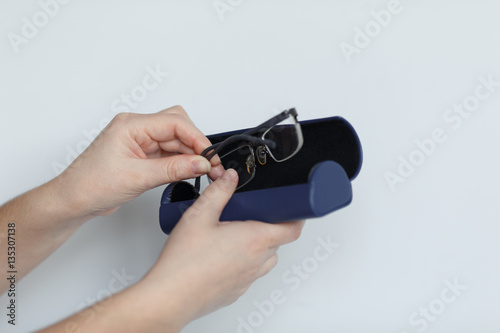 Hand holding glasses and blue case isolated on white background.