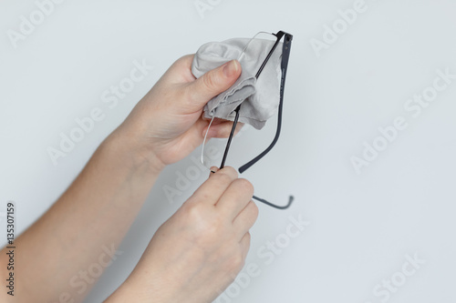 Women hand cleaning glasses lens with isolated background.
