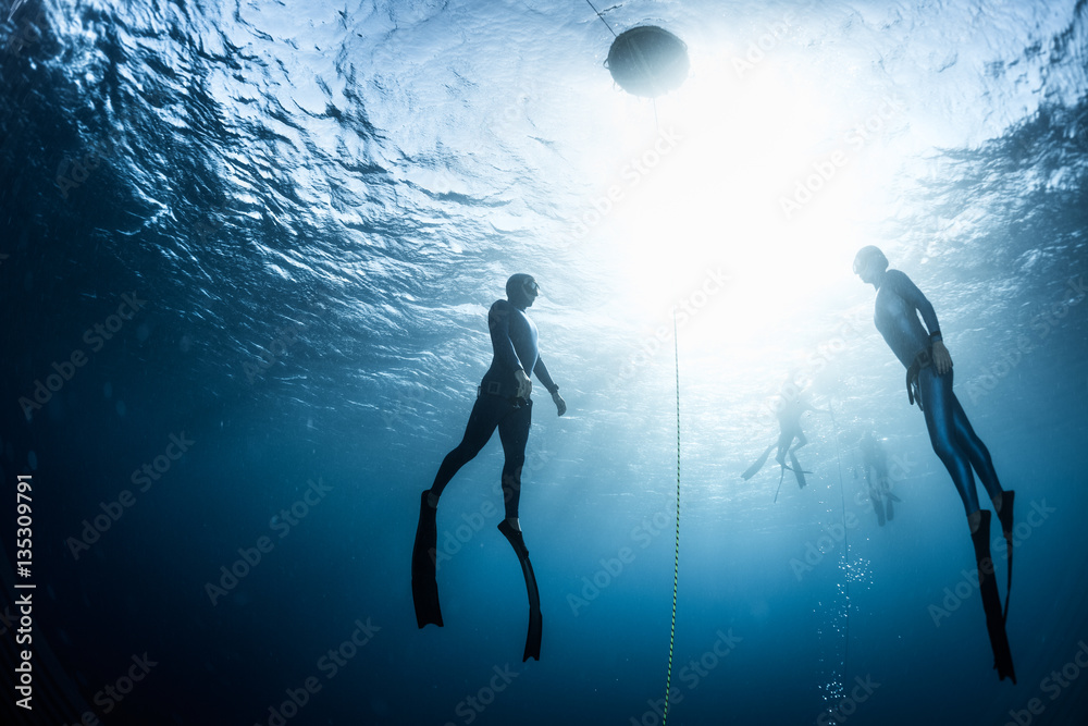 Two free divers, man and woman, ascending from the depth