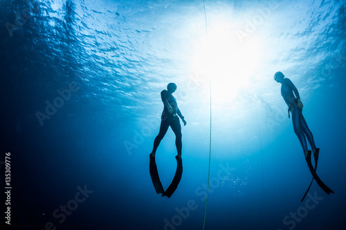 Two free divers, man and woman, ascending from the depth photo