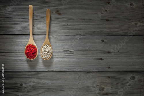 white pepper and goji berries on wooden spoons and wooden background