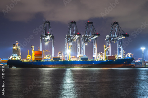 Containers loading by big crane at dark sunset, Shipping Trade Port