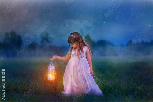 Fairytale portrait of Little girl with lightning at the night field