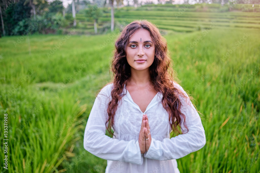 Yoga with view of green fields. Young woman with clasped hands. Concept of calm and meditation. Yoga with view of green fields. Young woman with clasped hands. Concept of calm and meditation.