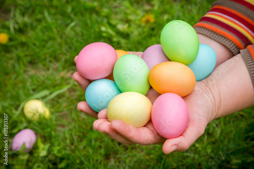 colorful easter eggs in hands on green lawn
