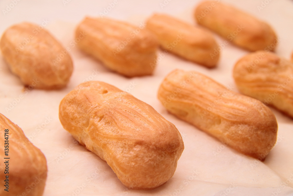 Long rows Eclair shells. Eclairs candy paper. The process of making cakes. Long rows Eclair shells. Eclairs candy paper. The process of making cakes.