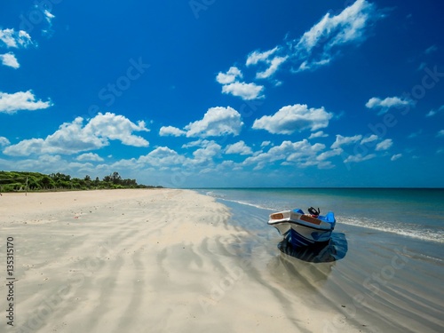 Isolated Boat on Amazing Beautiful scenic unspoiled white sand sandy beach with sand pattern and blue sky with white clouds near Pigeon Island in Trincomalee, Sri Lanka photo