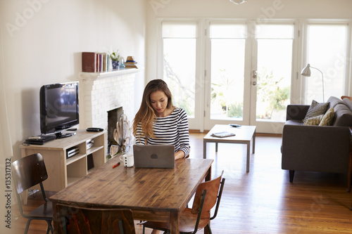 Woman Working From Home Using Laptop On Dining Table photo